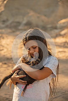 Portrait of adorable child with kitten. Baby girl holding hands a kitten in the light of sunset, pet, friend, lifestyle