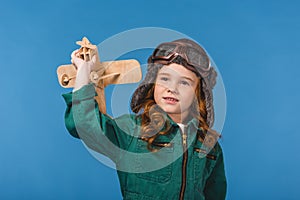 portrait of adorable child in pilot costume with wooden plane toy