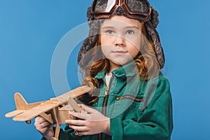 portrait of adorable child in pilot costume with wooden plane toy