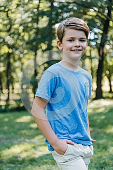 portrait of adorable child standing with hands in pockets and smiling at camera