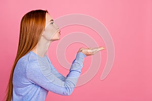 Portrait of adorable girl with foxy hairdo wear blue pullover look empty space send kiss on palms isolated on pink color