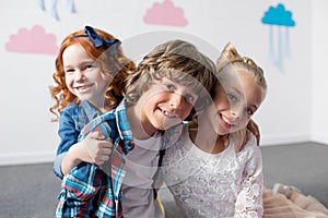 portrait of adorable happy kids smiling at camera while embracing