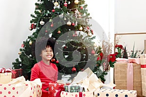 Portrait of adorable happy smiling African American girl child with black curry hair holding Christmas present gift box under