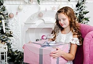 Portrait of adorable happy smiling little girl child in princess dress sitting in the chair with gift box