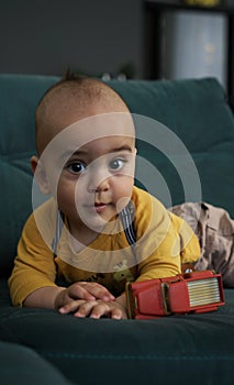 Portrait of adorable kid in yellow shirt lying on green couch