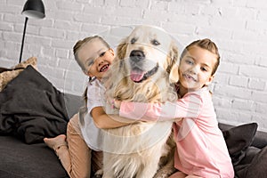 portrait of adorable kids hugging golden retriever dog