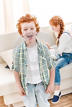 Portrait of adorable little boy laughing while little sister playing on sofa