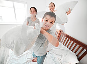 Portrait of adorable little boy, sister and mother having a fun pillow fight at home. Happy young family with mother and