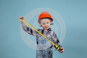 Portrait of adorable little caucasian kid wearing hard hat holding tape measure