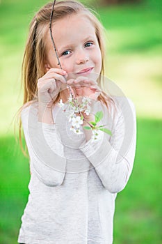 Portrait of adorable little girl in blooming apple tree garden on spring day