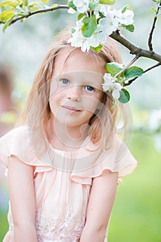 Portrait of adorable little girl in blooming apple tree garden on spring day