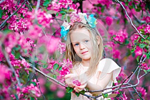 Portrait of adorable little girl in in blooming apple tree garden on spring day