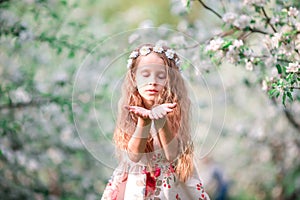 Portrait of adorable little girl in blooming cherry tree garden outdoors