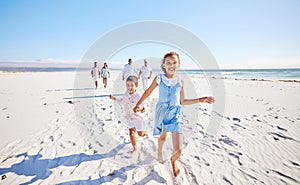 Portrait of adorable little girl and boy holding hands while running together on sandy beach while family follow in the