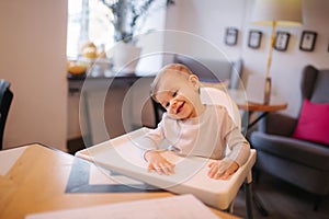 Portrait of adorable little girl on highchair. Baby laughing and play. Happy girl smile