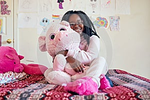I cant sleep without my best friend. Portrait of an adorable little girl holding a plush toy while sitting on her bed in