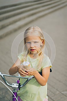 portrait of adorable little kid with ice cream and bicycle standing