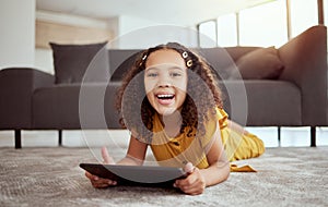 Portrait of adorable little mixed race child using digital tablet in home living room. One small cute hispanic girl