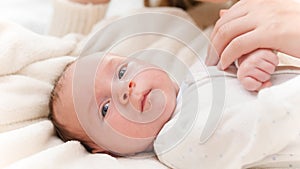 Portrait of adorable newborn baby and happy smiling mother. Mom tickling and playing with child in crib. Concept of