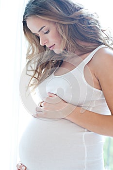 Portrait of adorable pregnant woman in white
