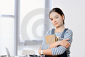 portrait of adorable preteen child standing with books