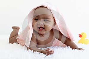 Portrait of adorable six month crawling African American baby covered in towel after bath time, happy smiling sweet little girl