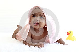 Portrait of adorable six month crawling African American baby covered in towel after bath time, happy smiling sweet little girl