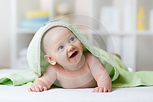 Portrait of adorable smiling baby in hooded towel lying on bed after having bathtime