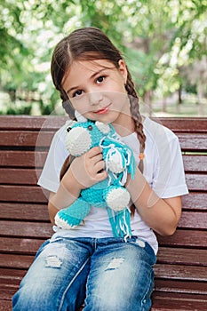 Portrait of adorable smiling little girl child with blue unicorn toy in park