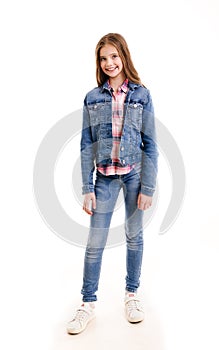 Portrait of adorable smiling little girl child preteen standing in jeans isolated