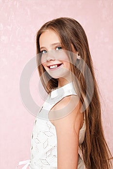 Portrait of adorable smiling little girl child schoolgirl teenager in dress with long hair standing