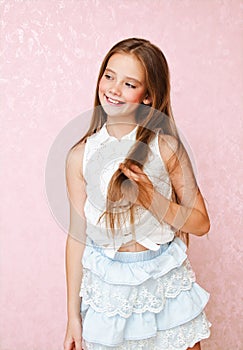 Portrait of adorable smiling little girl child schoolgirl teenager in dress with long hair standing