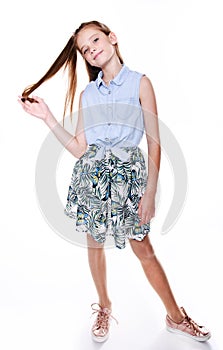 Portrait of adorable smiling little girl child schoolgirl teenager in dress with long hair standing isolated