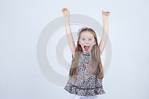 Portrait of adorable smiling little girl isolated on a white. Toddler with her hands up. Happy child. Cheerful and positive emotio