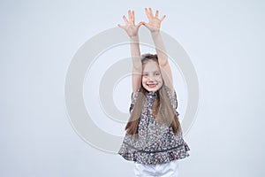 Portrait of adorable smiling little girl isolated on a white. Toddler with her hands up. Happy child. Cheerful and positive emotio