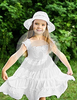 Portrait of adorable smiling little girl in white dress and hat