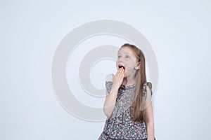 Portrait of adorable surprised astonished little girl isolated on a white. Girl child holding hands at the mouth surprised.