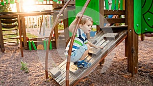 Portrait of adorable 3 years old boy climbing on ladder on the children palyground at park photo