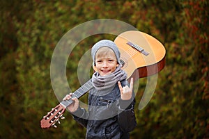 Portrait of adorable young boy with guitar on nature background