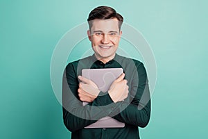 Portrait of adorable young freelancer man embrace netbook beaming smile on teal background