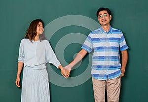 Portrait of adult Asian senior older man and woman, happy loving couple dressed casually holding hands and looking to the eyes of