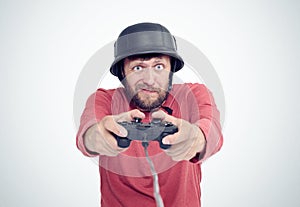 Portrait of adult bearded man in helmet holding joystick and playing videogames.