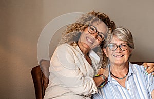 Portrait of adult beautiful daughter hugging her mother smiling, spending time together at home