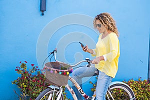 Portrait of adult beautiful young woman use phone and internet connection in outdoor leisure activity with the bike - blue and