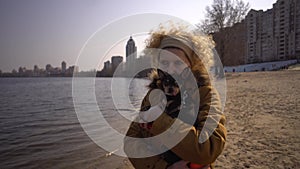 Portrait of an adult blonde curly hair Caucasian woman holding a small black-colored dog breed toy terrier. Old funny