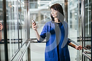 Adult businesswomen in suit using smartphone