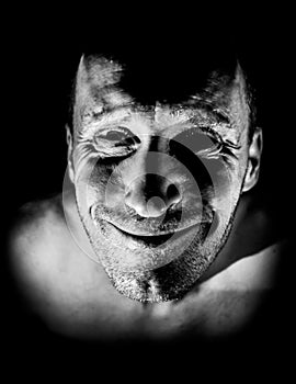 Portrait of adult caucasian man. He smiles like maniac and seems madness. Black and white shot, low-key lighting. Isolated on