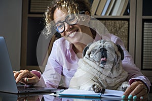 Portrait of adult cheerful young pretty woman and funny dog working together at laptop computer in home office room .- concept of