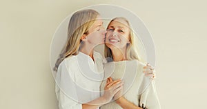 Portrait of adult daughter kissing her happy smiling caucasian middle aged mother