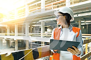 Portrait of adult female builder, engineer, architect, inspector, manager at construction site. Woman with plan, digital tablet photo